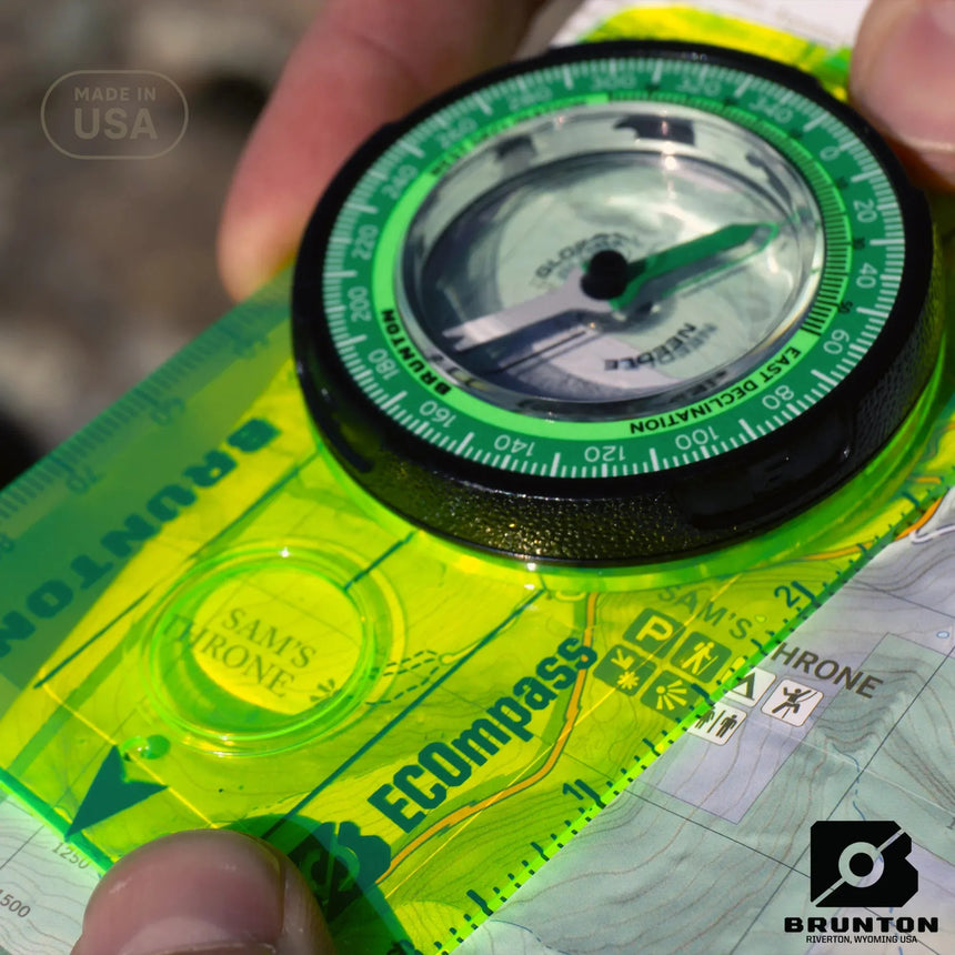 Brunton ECOcompass held over a map with a blurred background