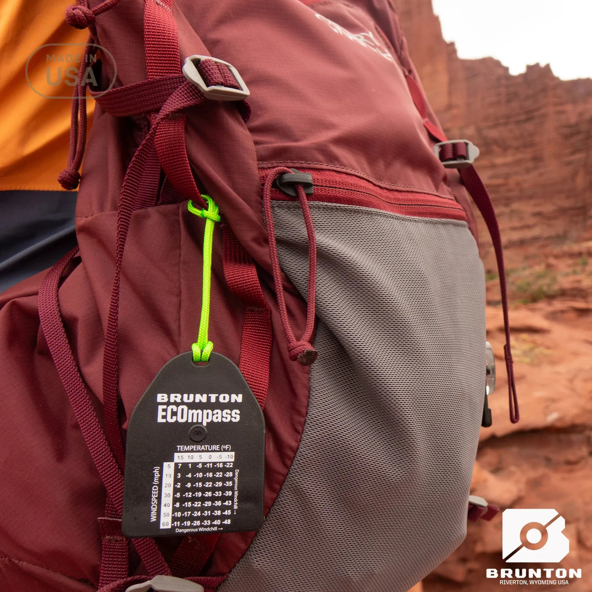 Person wearing a red backpack with a Brunton ECOpass temperature gauge tag in a desert setting.