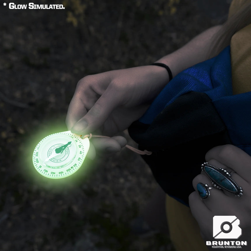 Glowing compass held by a person with a dark background