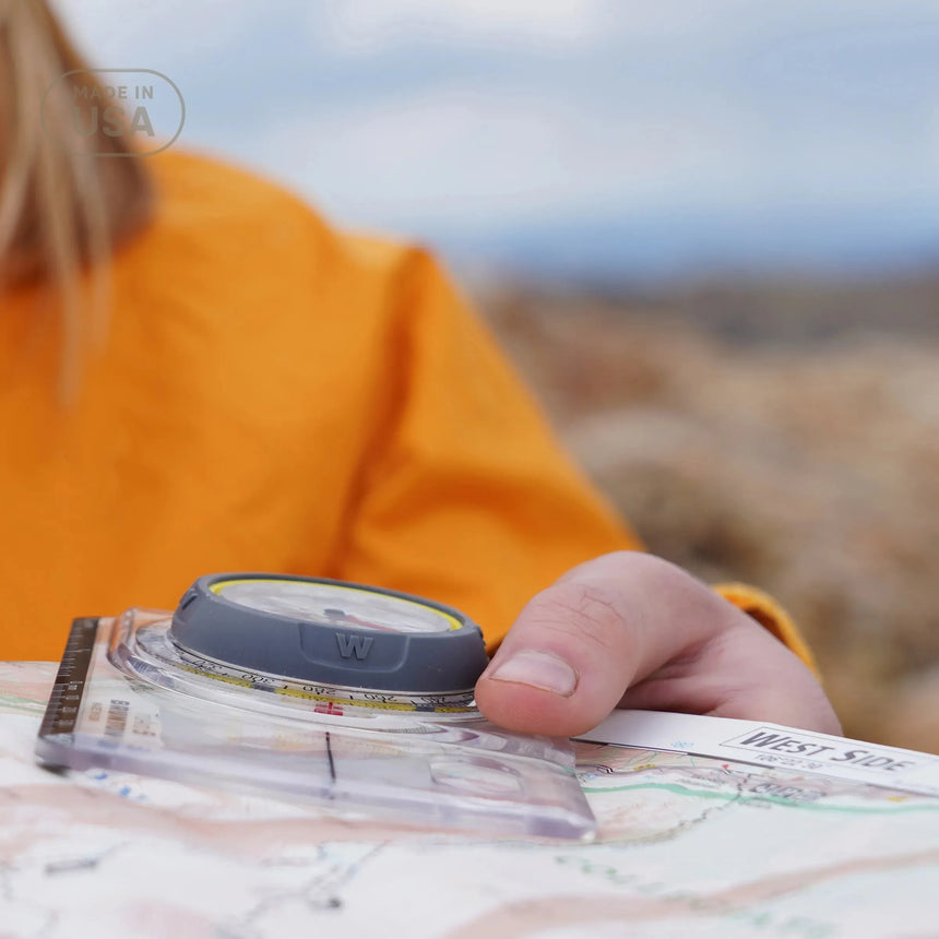 Person holding a compass and map outdoors
