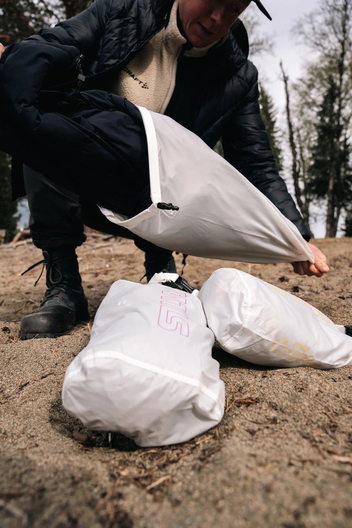 Person in a forest setting with white bags on the ground