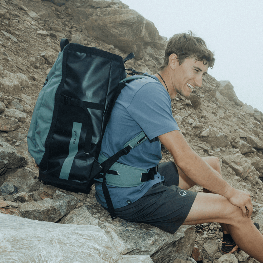 Wild Country Climbing Crag Hauler 40 Backpack Outdoor Action Black/Marsh - Model with pack sitting on rock