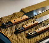 Benchmade 4000-02 three-piece kitchen knife set in Maple Valley Richlite, laid out in knife roll
