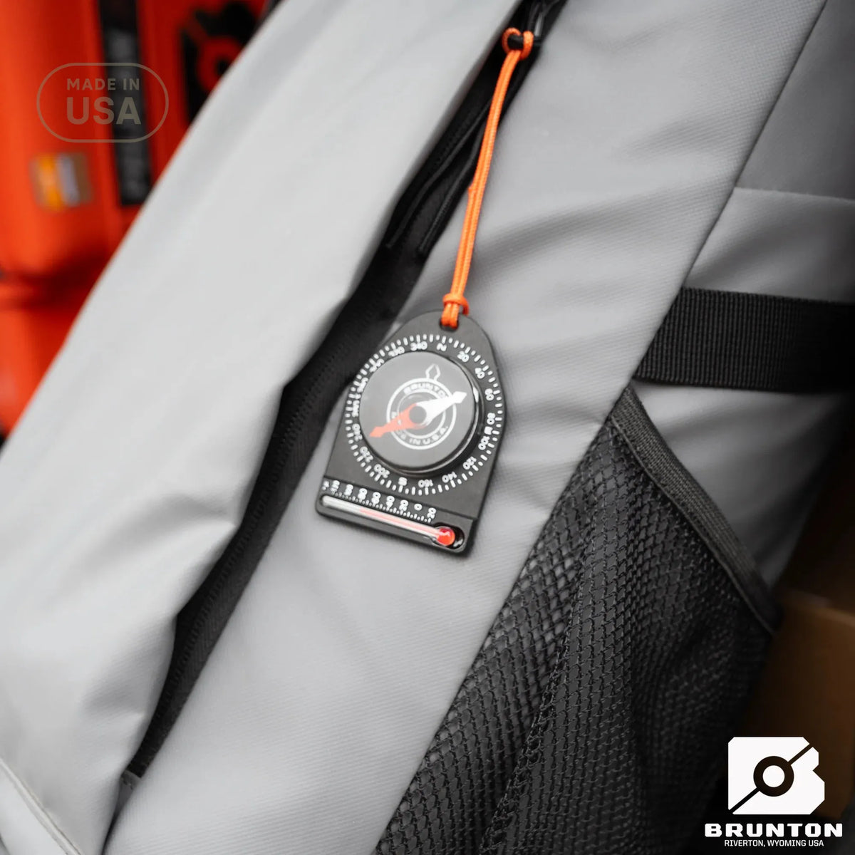 Brunton compass attached to a backpack with visible brand logo.