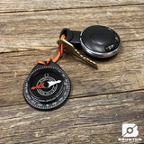 Compass and keychain with Brunton logo on a wooden surface