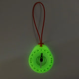 Glowing green compass with a red string on a dark background