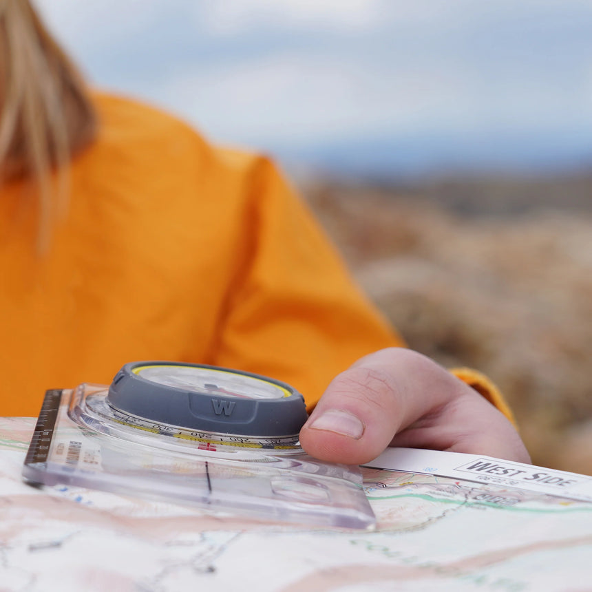 Person holding a compass and map outdoors