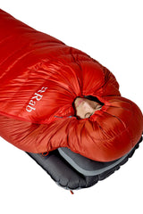 Rab Alpine Down Sleeping Bag (-18°C/0F) in Dark Horizon/Tuscan Red - Model Lying Wrapped on Mat, Alternate Angle