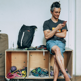 Wild Country Climbing Flow Back Pack - person sitting on box with pack next to them