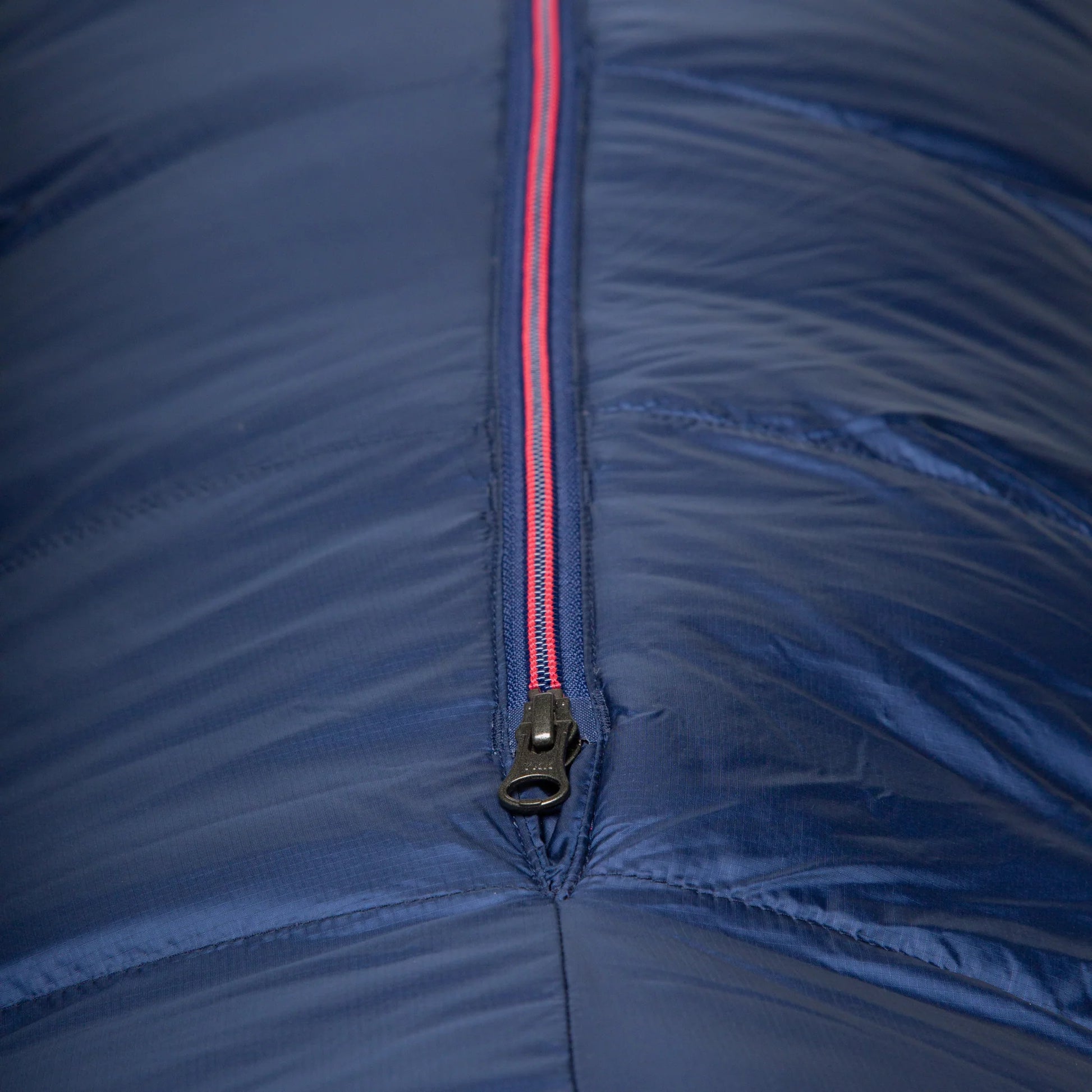 Mountain Equipment Helium 800 Women's Sleeping Bag in Medieval Blue packed into waterproof roll-top stuff sack showing compact 30 x 24 x 23 cm packed size