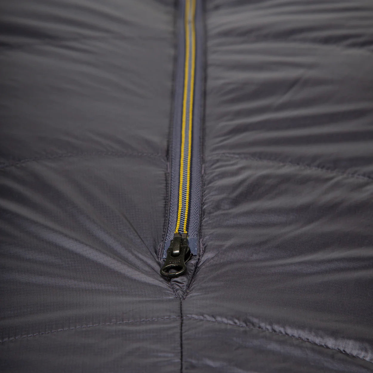Mountain Equipment Helium GT 250 Sleeping Bag in Anvil Grey packed into waterproof roll-top stuff sack showing lightweight packable construction