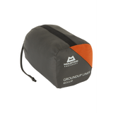 Mountain Equipment Groundup Mummy Sleeping Bag Liner in Paprika in stuff sack showing lightweight packable construction